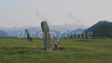 女游客在阿尔泰山考察突厥时期的古石柱